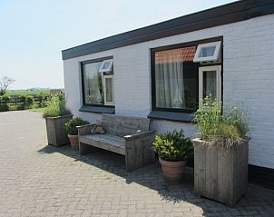 Front view of vacation home Duinviooltje with wooden bench, De Cocksdorp, Texel.
