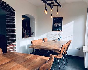 Eetruimte met houten tafels en industrile lampen in Vakantiehuis De Muy, De Cocksdorp, Texel.