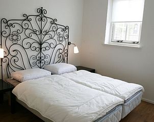 Schlafzimmer in Typ 7 - 2107 Ferienhaus De Cocksdorp Texel mit elegantem, schmiedeeisernem Kopfteil.