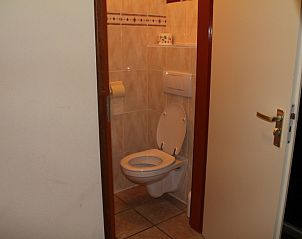 Moderne badkamer in Duin-/vuurtorenzicht vrijstaand vakantiehuis in De Cocksdorp, Texel met toilet en tegelmuur.