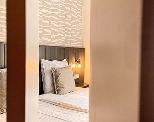 Zicht op slaapkamer Vakantiehuis Hogezandskil, Texel vanuit de gang met sfeervolle verlichting.