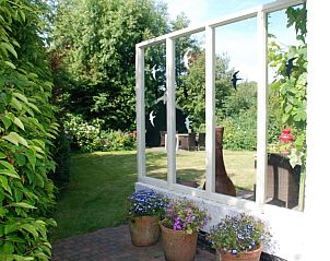 Groene tuin bij Het Wulpenlied vakantiehuis in De Cocksdorp Texel met kleurrijke bloemen.