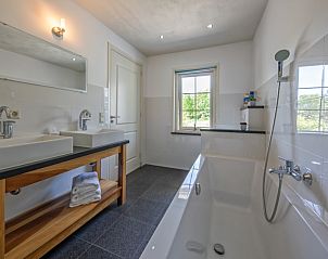 Moderne badkamer met bad en dubbele wastafel in Vakantiehuis Paal 86, Texel.