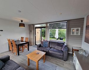 Lichte woonkamer van Bungalow 174 op Texel met uitzicht op de tuin en moderne meubels.