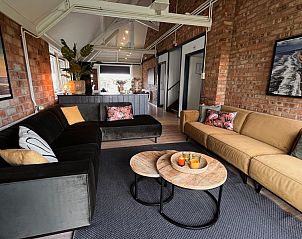 Ruime leefruimte in Noorderwind vakantiehuis, De Cocksdorp, Texel met uitnodigende banken en sfeervolle verlichting.