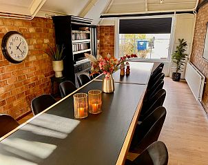 Gezellige eetruimte in Noorderwind, De Cocksdorp, Texel met decoratieve elementen en boekenplank.