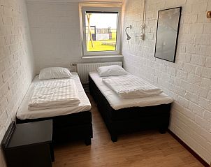 Slaapkamer in Noorderwind vakantiehuis, De Cocksdorp, Texel met twee comfortabele bedden en uitzicht op de tuin.