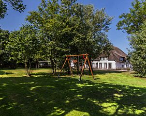 Speelplaats in de tuin van Type T-4 vakantiehuis, De Cocksdorp, Texel, omgeven door groen.
