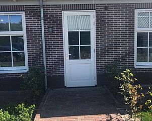 Voordeur van Appartement C in De Cocksdorp, Texel, omringd door een bloementuin.