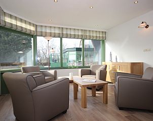 Light seating area in Villa De Witte Hoek conservatory, De Cocksdorp, Texel, overlooking the garden.
