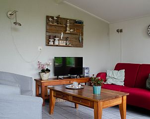 Cozy living room in 9600 - Daalder - Comfort vacation home De Cocksdorp Texel with red couch and TV.