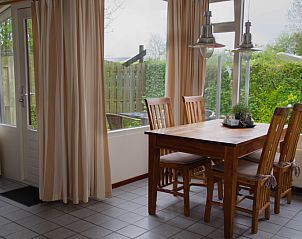 Dining area in 9600 - Daalder - Troost vacation home De Cocksdorp Texel with wooden table and chairs by window.