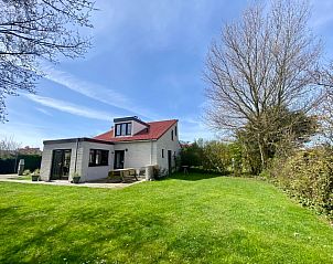 Vakantiehuis D 491 in De Cocksdorp, Texel, biedt een prachtig uitzicht op een groene tuin en blauwe lucht, ideaal voor een ontspannen verblijf.