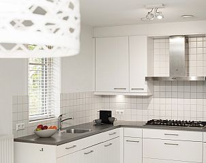 Lichte slaapkamer met tweepersoonsbed in Sluftervallei bungalow, Texel.