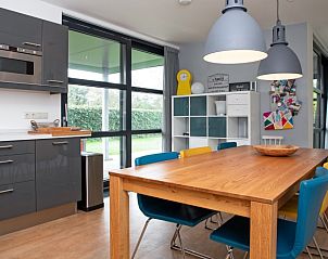 Lichte eetruimte in Vakantiehuis Slufteroord 240, De Cocksdorp met uitzicht op de tuin en kleurrijke stoelen.