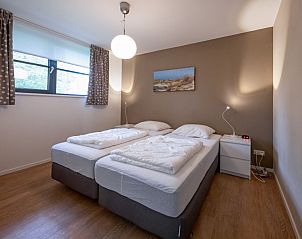 Comfortabele slaapkamer in Vakantiehuis Slufteroord 240, Texel met twee eenpersoonsbedden en sfeervolle verlichting.