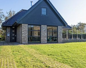 Voorzijde van Vakantiehuis Slufteroord 240, Bungalowpark Slufteroord, Texel met grote ramen en groene omgeving.