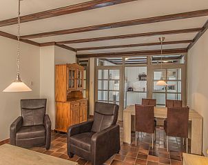 Eet- en zitgedeelte in Type R vakantiewoning, De Cocksdorp, Texel, met houten meubels en warme sfeer.