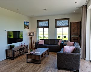Comfortabele woonkamer in Vakantiehuis Texel, De Cocksdorp, met uitzicht op het groene landschap.