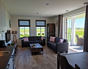 Open woonkamer in Vakantiehuis Texel, De Cocksdorp, met toegang tot het terras en uitzicht op de natuur.