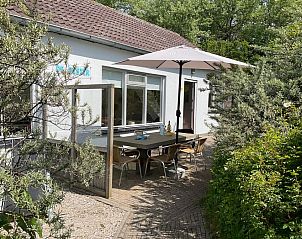 Gezellig terras bij Bungalow Schelpenoord - Vakantiehuis De Oester in De Cocksdorp, Texel, met parasol en tuinmeubilair.