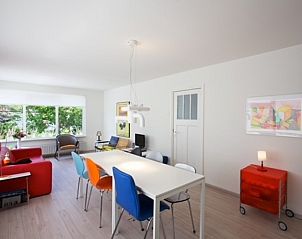 Lichte woonkamer in Bungalow Schelpenoord - Vakantiehuis De Oester, De Cocksdorp, Texel, met kleurrijke stoelen en moderne inrichting.