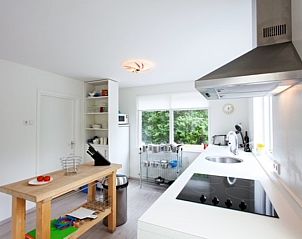 Moderne keuken in Bungalow Schelpenoord - Vakantiehuis De Oester, De Cocksdorp, Texel, met kookplaat en uitzicht op de tuin.