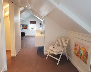 Stijlvolle zolderruimte in Bungalow Schelpenoord - Vakantiehuis De Oester, De Cocksdorp, Texel, met zitgedeelte en kunst aan de muur.