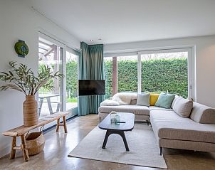 Cozy living room with large window in Holiday home De Razende Bol, De Cocksdorp, Texel, overlooking the garden.