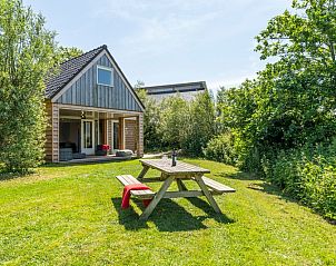 Gemtliches Ferienhaus Zeewinde in De Cocksdorp, Texel, mit einer einladenden Terrasse und grner Umgebung.