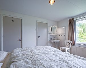 Lichte slaapkamer in vakantiehuis Muyweg 062, De Cocksdorp, Texel met eigen wastafel en uitzicht op de tuin.