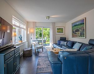 Gemtliches Wohnzimmer des Ferienhauses Noordhoorn in De Cocksdorp, Texel mit komfortabler Einrichtung und Blick auf den grnen Garten.