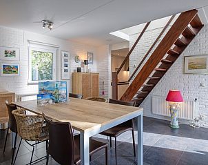 Gemtliche Essecke im Ferienhaus Noordhoorn, De Cocksdorp, Texel. Moderne Einrichtung mit Holztreppe und Kunst an den Wnden.