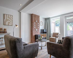 Lichte woonkamer van Vakantiehuis Slufterhoek 104 in De Cocksdorp, Texel met moderne meubels en grote ramen.