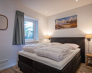 Comfortabele slaapkamer in Vakantiehuis Slufterhoek 104, De Cocksdorp, Texel met groot bed en sfeervolle verlichting.