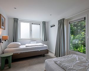 Lichte slaapkamer in Vakantiehuis Slufterhoek 104, De Cocksdorp, Texel met eenpersoonsbedden en uitzicht op de tuin.