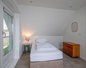 Knusse slaapkamer in Vakantiehuis Slufterhoek 104, De Cocksdorp, Texel met eenpersoonsbed en houten ladekast.