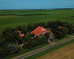 Luchtfoto van Vakantiehuisje in De Cocksdorp, Texel, omgeven door weelderige natuur en groene velden op de Waddeneilanden.