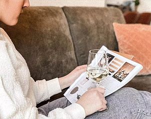 Ontspanning in Vakantiehuisje in De Cocksdorp, Texel met een glas wijn en tijdschrift, genietend van het comfort op de Waddeneilanden.