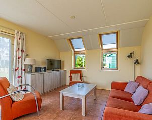 Lichte woonkamer in Vakantiehuisje in De Cocksdorp, Texel met comfortabele zithoek en uitzicht op de tuin, ideaal voor ontspanning.
