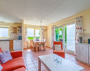 Lichte woonkamer van Vakantiehuisje in De Cocksdorp, Texel met uitzicht op groene natuur en ruime eethoek, ideaal voor ontspanning.