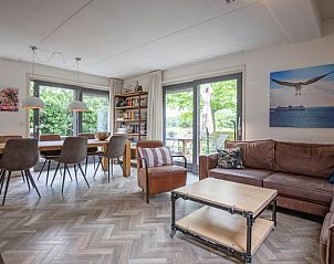 Gezellige woonkamer in Vakantiehuis in De Cocksdorp, Texel met ruime zithoek en uitzicht op groene tuin, ideaal voor ontspanning op de Waddeneilanden.