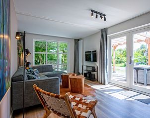 Lichte woonkamer van Vakantiehuis D 690 in De Cocksdorp, Texel, met moderne inrichting en uitzicht op het terras en de natuur.