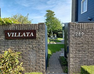 Ingang van Vakantiehuis B 289 in De Cocksdorp, Texel, omgeven door een groene tuin en rustieke stenen muren.