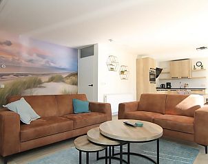 Gezellige woonkamer in Vakantiehuis D 617 in De Cocksdorp, Texel. Comfortabele zithoek met strandthema en moderne keuken.