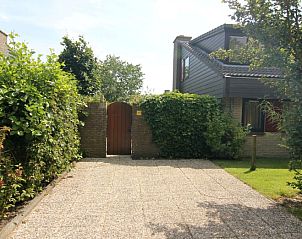 Entree van Vakantiehuis B 373 in De Cocksdorp, Texel, omgeven door groene natuur en rustieke stenen muren.