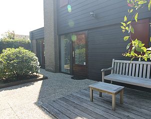 Rustige patio van Vakantiehuis B 373 in De Cocksdorp, Texel, met houten bank en groene omgeving voor een ontspannen verblijf.
