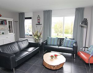 Gezellige woonkamer in Vakantiehuis A 381, De Cocksdorp, Texel met comfortabele zitbanken en uitzicht op de groene tuin.