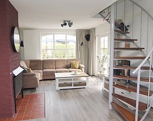 Gezellige woonkamer in Vakantiehuis E 632, De Cocksdorp, Texel, met comfortabele zithoek en wenteltrap, ideaal voor ontspanning.