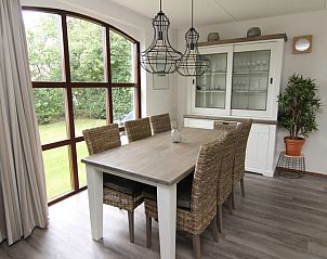 Gezellige eetkamer in Vakantiehuis E 632, De Cocksdorp, Texel met uitzicht op de groene tuin en moderne inrichting.